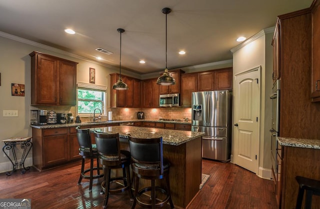 kitchen with appliances with stainless steel finishes, a kitchen island, dark wood-type flooring, backsplash, and recessed lighting