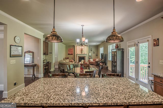 kitchen with light stone counters, baseboards, a kitchen island, crown molding, and dark wood-style flooring