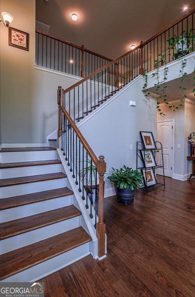 stairs with baseboards, wood finished floors, and a high ceiling