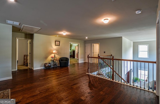 hallway with attic access, wood finished floors, baseboards, and an upstairs landing