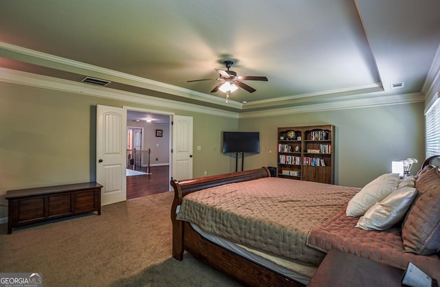 carpeted bedroom with a raised ceiling, crown molding, and a ceiling fan