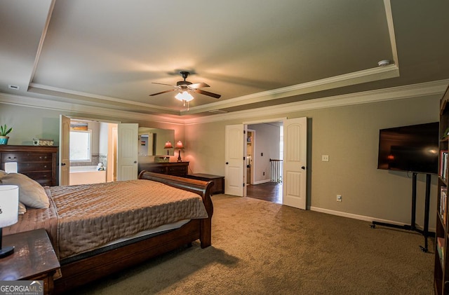 bedroom featuring a tray ceiling, carpet, baseboards, ornamental molding, and ensuite bath