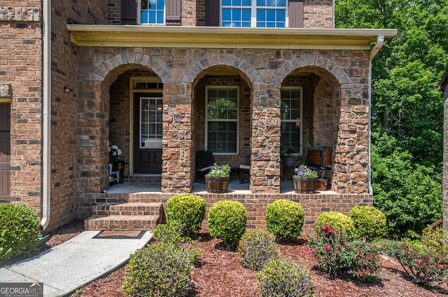entrance to property with a porch and brick siding