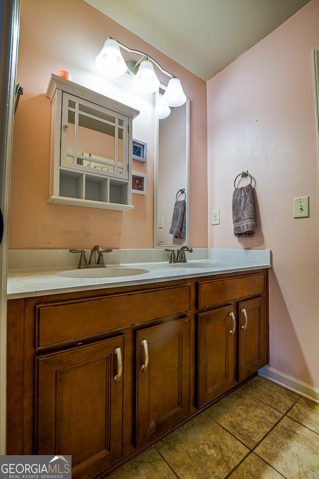 bathroom with double vanity, tile patterned floors, and baseboards