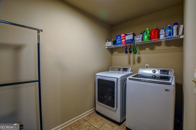 laundry area featuring washer and clothes dryer, light tile patterned flooring, and baseboards