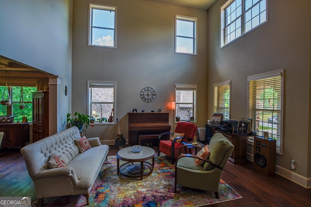 living room with a towering ceiling, wood finished floors, and baseboards