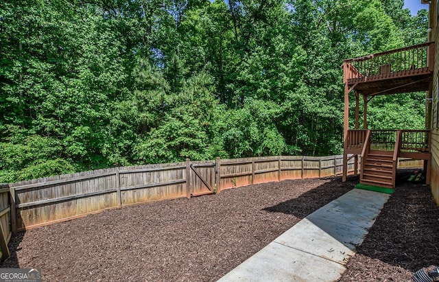fenced backyard with a deck, stairway, and a gate