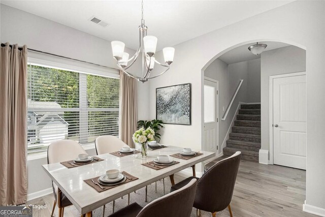 458 Ajo Way, Dallas, GA 30157 - dining space featuring arched walkways, light wood-type flooring, a chandelier, and stairway