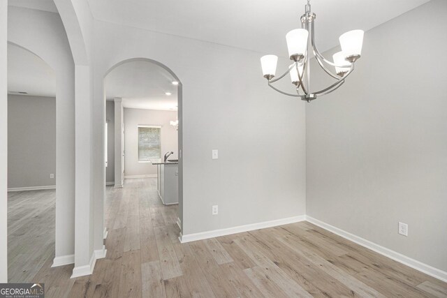 458 Ajo Way, Dallas, GA 30157 - spare room featuring a chandelier, light wood finished floors, and arched walkways