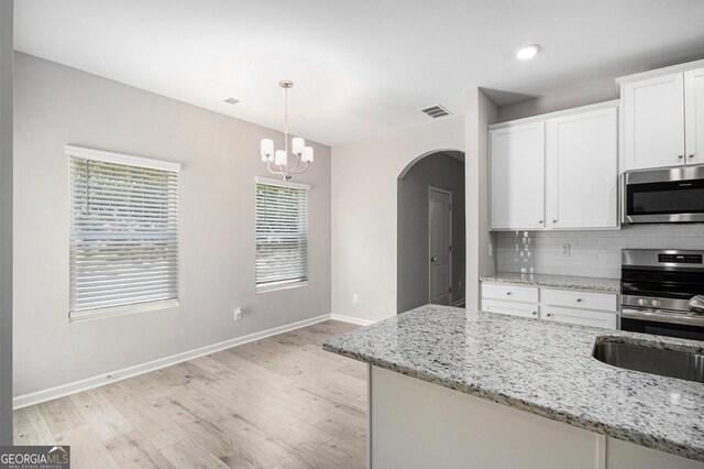458 Ajo Way, Dallas, GA 30157 - kitchen featuring appliances with stainless steel finishes, arched walkways, light wood finished floors, tasteful backsplash, and white cabinets