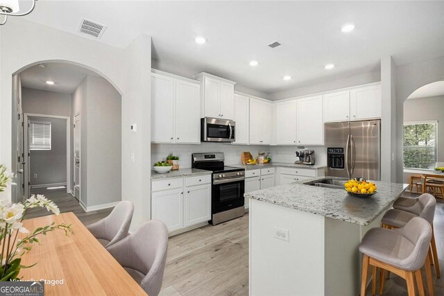 458 Ajo Way, Dallas, GA 30157 - kitchen with appliances with stainless steel finishes, arched walkways, light wood-type flooring, tasteful backsplash, and light stone counters