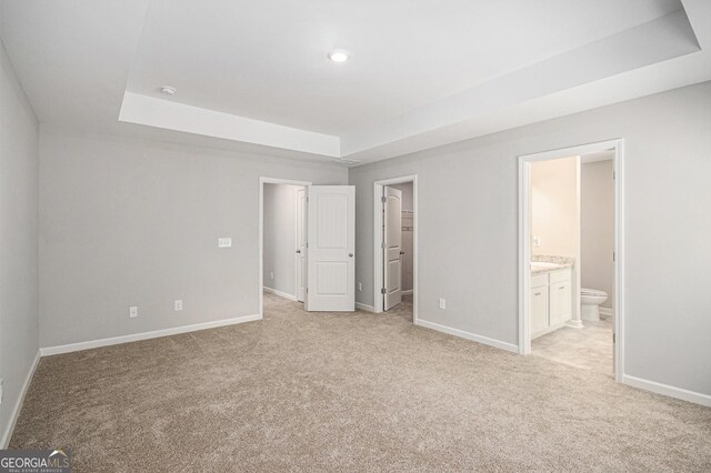 458 Ajo Way, Dallas, GA 30157 - unfurnished bedroom with a tray ceiling, light carpet, a spacious closet, and connected bathroom