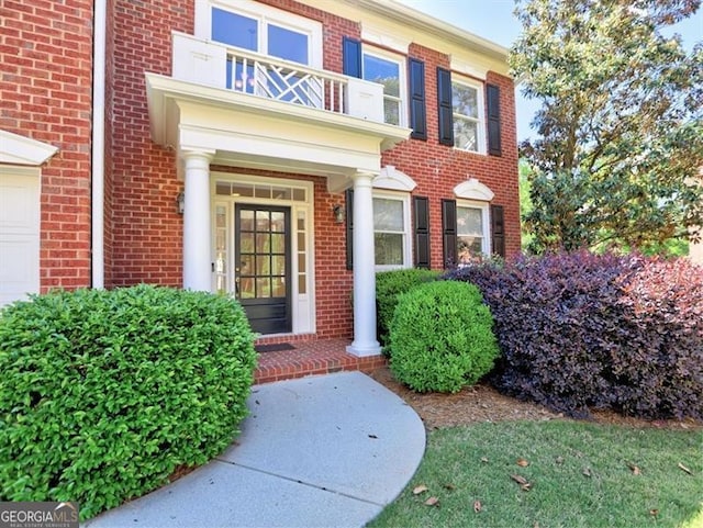 doorway to property with brick siding, a balcony, and a garage