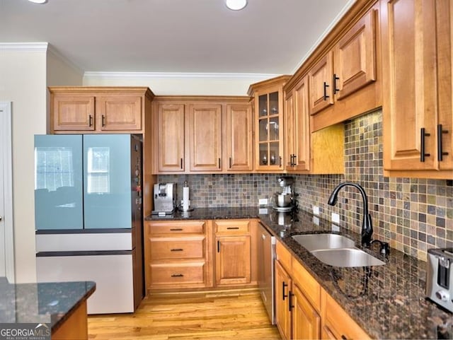 kitchen featuring a sink, crown molding, dishwasher, dark stone counters, and brown cabinetry