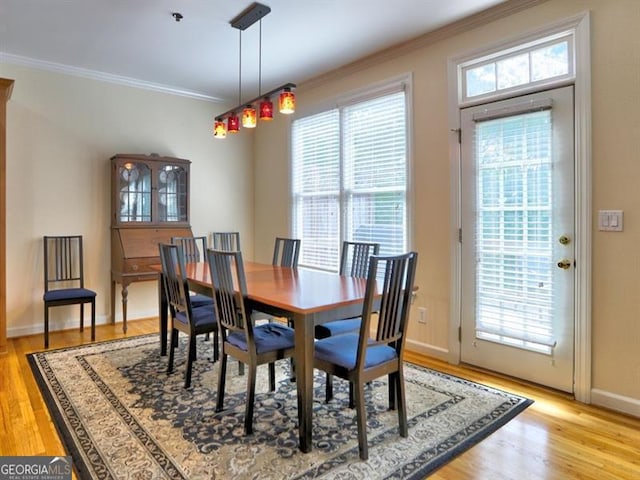 dining space featuring ornamental molding, plenty of natural light, light wood finished floors, and baseboards