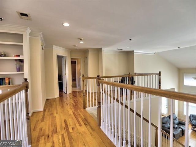 corridor featuring an upstairs landing, ornamental molding, light wood-style floors, and recessed lighting