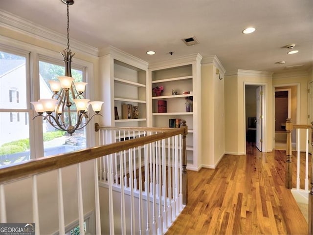 hallway featuring a chandelier, ornamental molding, light wood-type flooring, an upstairs landing, and recessed lighting