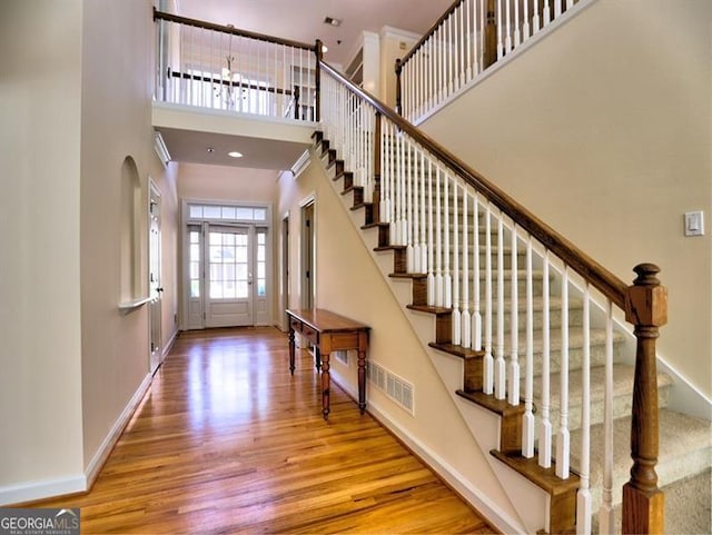 foyer featuring wood finished floors, a towering ceiling, baseboards, and stairway