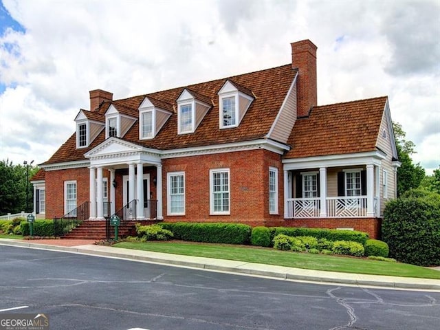 view of front of house featuring a chimney and brick siding