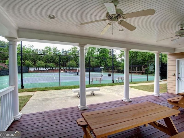 wooden deck with a tennis court, ceiling fan, and fence