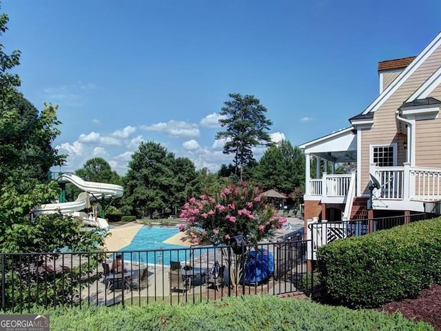 view of pool featuring a water slide and fence
