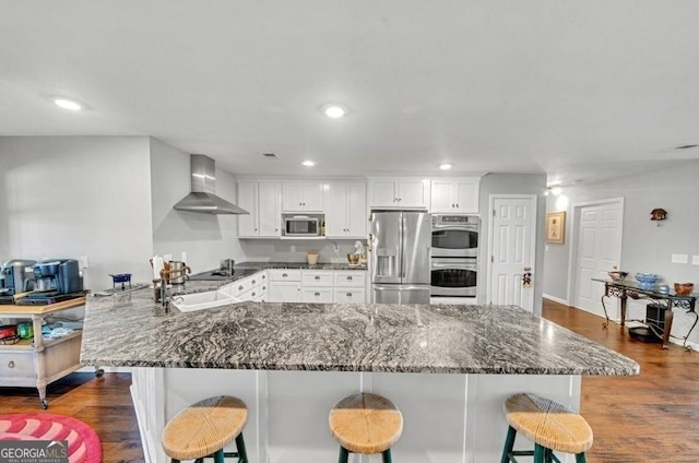 762 Old Mcleod Bridge Rd, Adrian, GA 31002 - kitchen with stainless steel appliances, wall chimney range hood, a kitchen breakfast bar, dark wood-style flooring, and recessed lighting