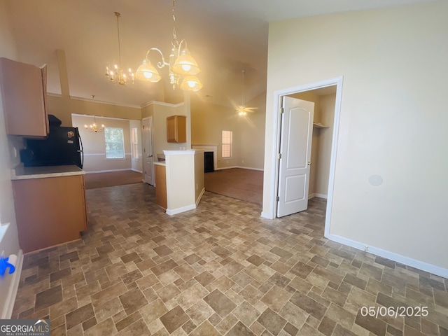 kitchen with freestanding refrigerator, a chandelier, a towering ceiling, stone finish floors, and baseboards