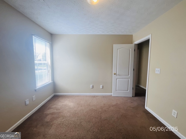 carpeted spare room with baseboards and a textured ceiling