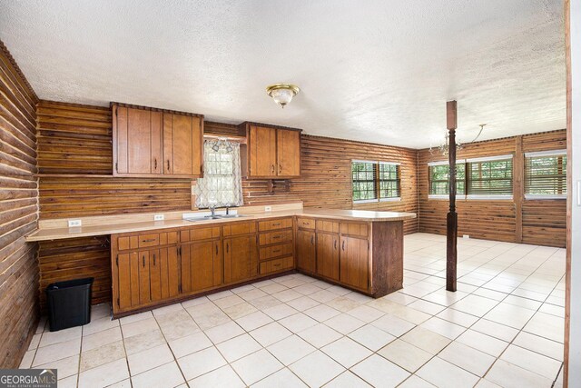 1795 Hutcheson Ferry Rd, Whitesburg, GA 30185 - kitchen with a textured ceiling, a sink, light countertops, a peninsula, and brown cabinets