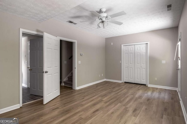 175 Hearth Way, Fairburn, GA 30213 - unfurnished bedroom with wood finished floors, baseboards, a textured ceiling, a closet, and a ceiling fan