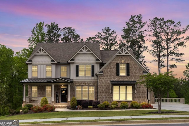 craftsman-style house with a porch, brick siding, a lawn, and driveway