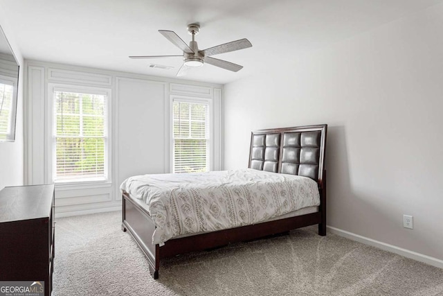 carpeted bedroom featuring multiple windows, a ceiling fan, and baseboards