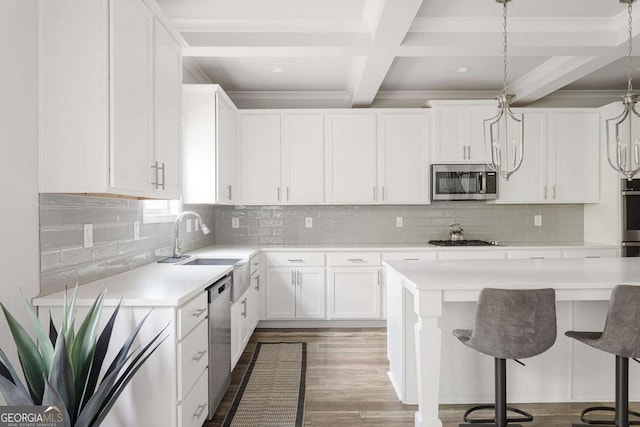 kitchen with stainless steel appliances, light countertops, a kitchen breakfast bar, beam ceiling, and white cabinets