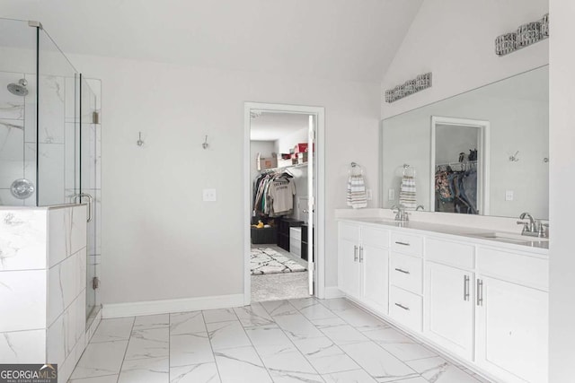 bathroom with marble look tiles, a marble finish shower, a spacious closet, double vanity, and baseboards