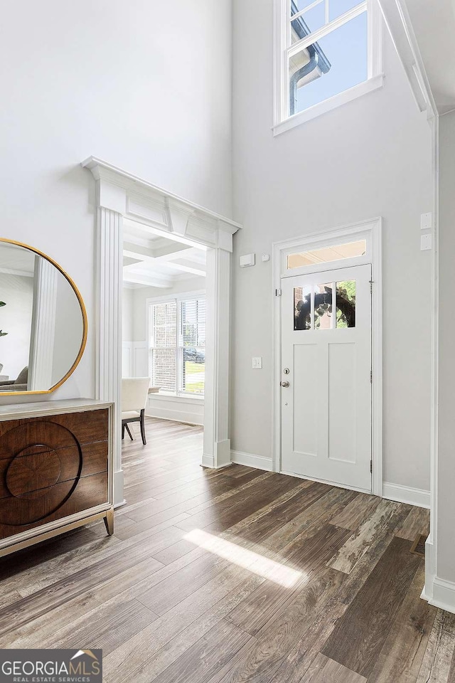 foyer featuring wood finished floors, a high ceiling, and baseboards