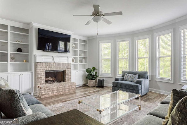 living area featuring plenty of natural light, wood finished floors, baseboards, crown molding, and a brick fireplace