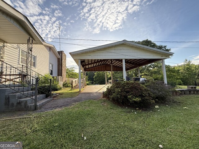 view of grassy yard featuring a detached carport and driveway
