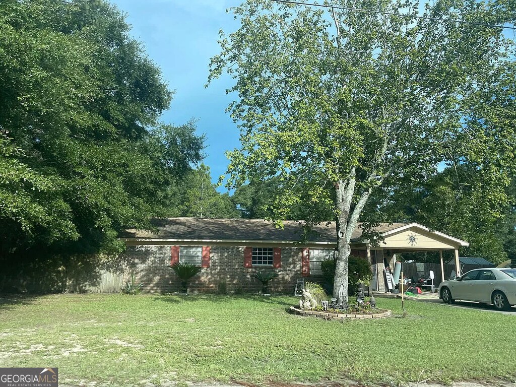 view of front of home with an attached carport and a front lawn