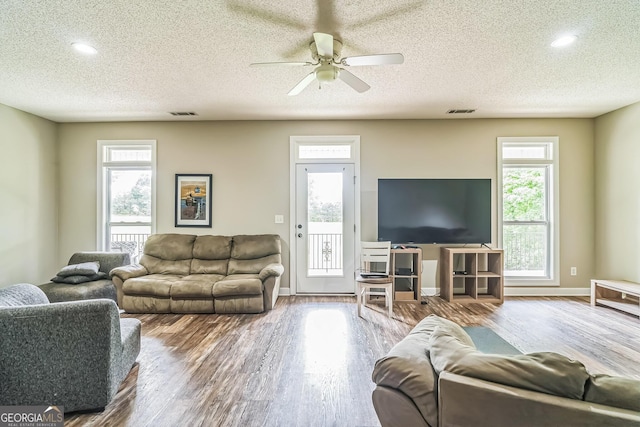living area with wood finished floors, a textured ceiling, a ceiling fan, plenty of natural light, and recessed lighting