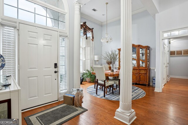 132 Eagles Club Dr, Stockbridge, GA 30281 - foyer featuring decorative columns, healthy amount of natural light, crown molding, wood finished floors, and a chandelier