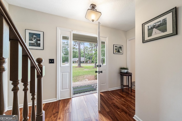 foyer entrance featuring dark wood-style floors, baseboards, stairs, and a textured ceiling