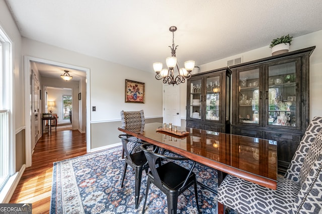dining space with a chandelier, wood finished floors, and baseboards