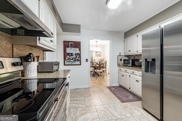 kitchen featuring appliances with stainless steel finishes, extractor fan, decorative backsplash, white cabinets, and baseboards