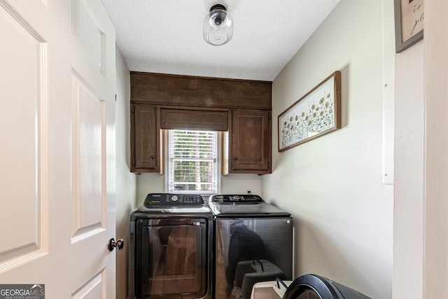 laundry area with cabinet space, washer and dryer, and a textured ceiling