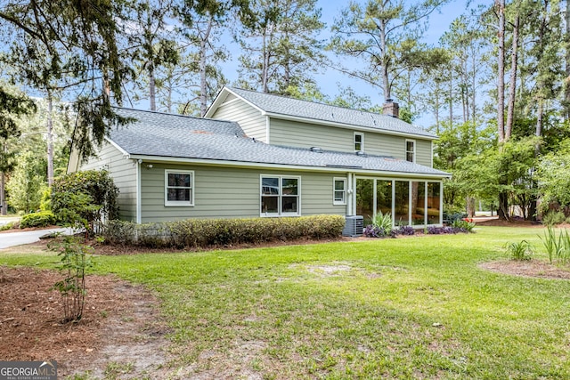 back of property with central air condition unit, a chimney, a yard, a sunroom, and roof with shingles