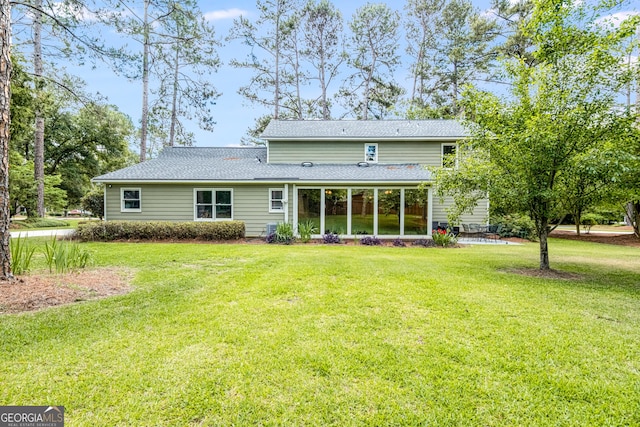rear view of property featuring a yard, roof with shingles, and a sunroom