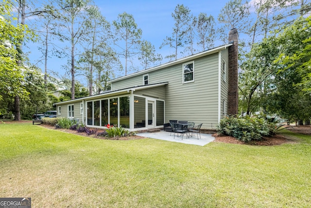back of property featuring a chimney, a lawn, and a patio
