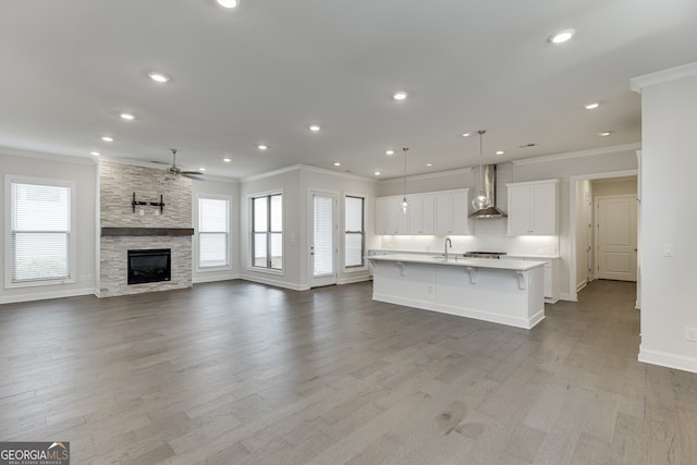 1023 Harvest Park Ln, Suwanee, GA 30024 - kitchen with wall chimney range hood, a ceiling fan, a sink, healthy amount of natural light, and ornamental molding