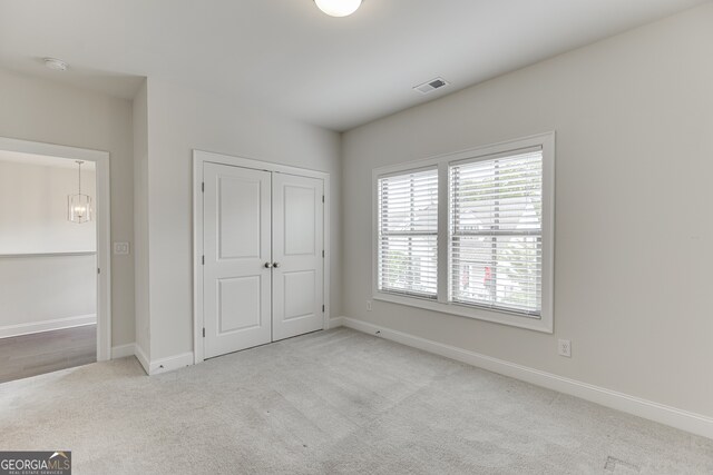 1023 Harvest Park Ln, Suwanee, GA 30024 - unfurnished bedroom with carpet, baseboards, a closet, and a chandelier