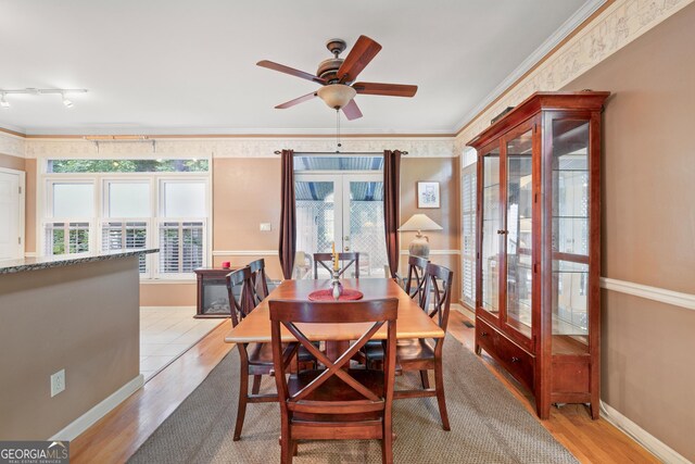 dining space featuring wood finished floors, ceiling fan, track lighting, french doors, and ornamental molding